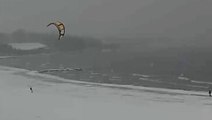 Wind skier glides across snow-covered beach in Cleveland as waves buffet shore