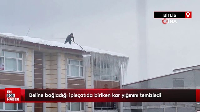 Beline bağladığı iple çatıda biriken kar yığınını temizledi