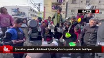 Gazze'de yerinden edilmiş çocuklar, bir kap sıcak yemek için kuyrukta bekliyor