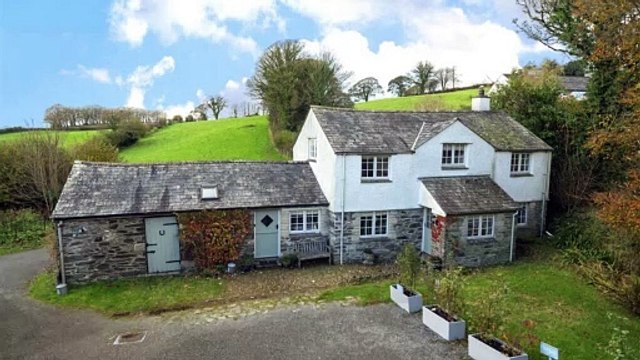 Charming cottage for sale sits beside a stream and has countryside views