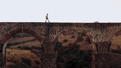 Drone footage of man walking bridge