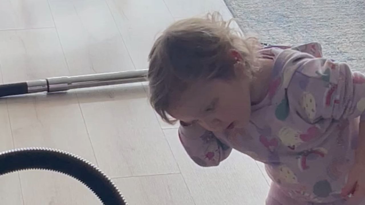 Sweet toddler girl tries drying her hair with the Hoover Vacuum Cleaner