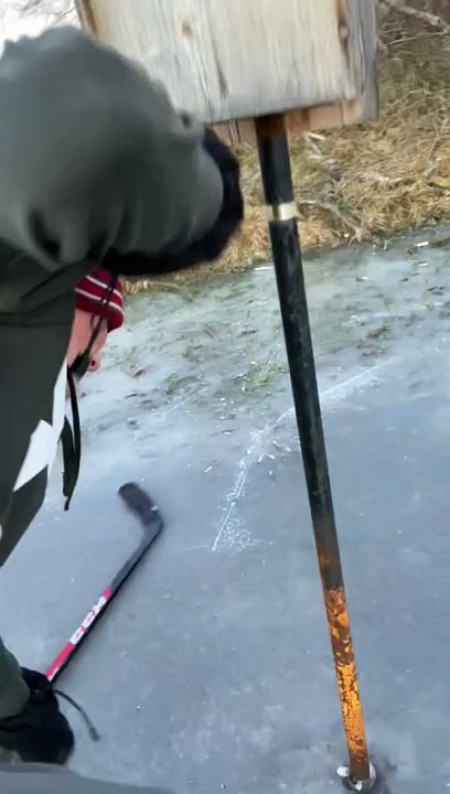 Boy with hockey stick gets his tongue stuck on pole on icy surface