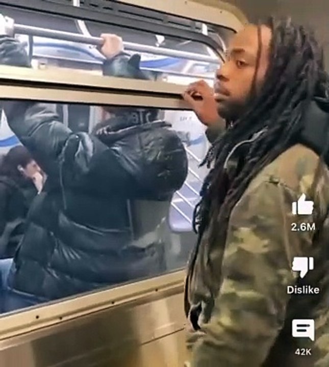 Guy stands beside subway window and a man snatches his toboggan off his head