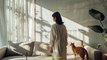 Realistic photo of a woman walking in her living room with her brown cat. Large white wall,Midjourney prompts