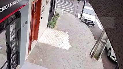 Por outro ângulo, Palio passa reto, atinge carro estacionado e tomba em calçada no Centro