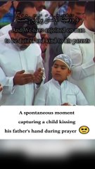 A child kissing his father's hand while praying!