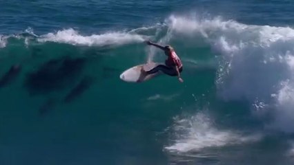 Un grupo de delfines acompaña y aúpa a la victoria a una surfista hawaiana en Australia