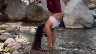 Woman Performs Handstand Variations on the Banks of Small Stream