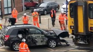 Car is pulled off the tracks after being crushed by train at crossing