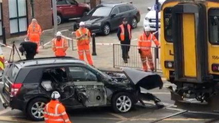 Car is pulled off the tracks after being crushed by train at crossing