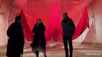 Fili rossi e grandi abiti fluttuanti in un ex campo di concentramento
