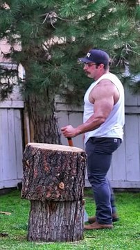 A bodybuilder is chopping wood.