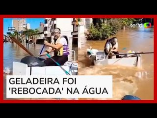 Homem utiliza geladeira para atravessar bairro alagado em Porto Alegre