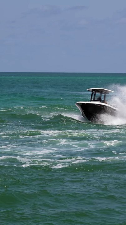 Robalo boat splashing on a wavy Sunday at the Haulover Inlet in Miami, Florida