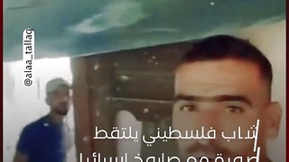 شاب فلسطيني يلتقط صورة مع صاروخ إسرائيلي اخترق منزله ولم ينفجر