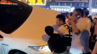 Menschenmenge arbeitet daran, Auto von einem nach Kollision eingeklemmten Mann abzuheben