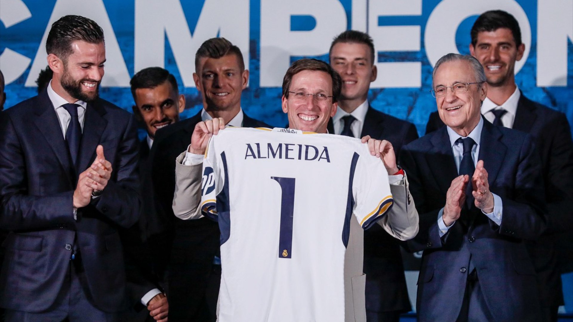 Almeida se resiste con humor a ponerse una camiseta del Real Madrid.