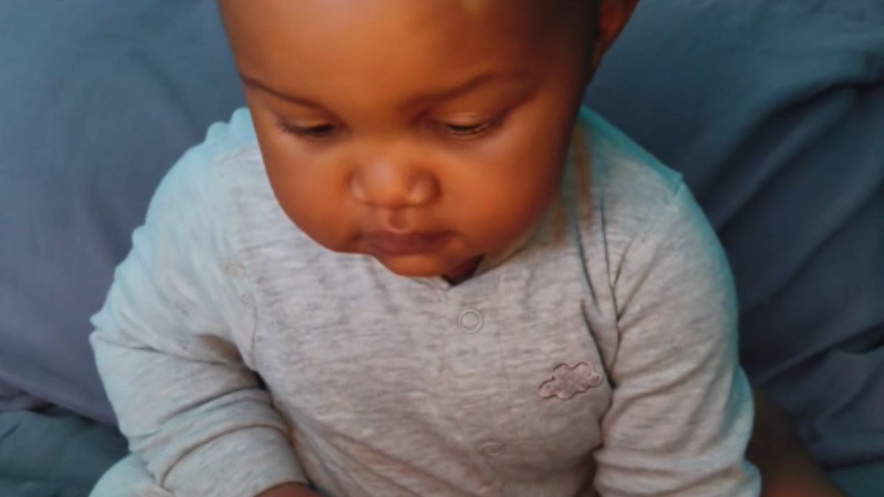 Tiny hand meets the dance of the flame on a first birthday cake