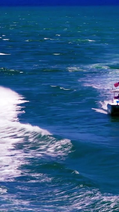 Watch the small catamaran deal with the wake of the big Fire Rescue boat at the Haulover Inlet in Bal Harbour, Florida
