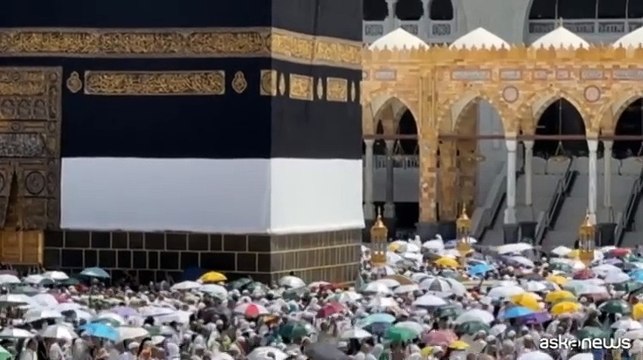Pellegrini alla Mecca girano intorno alla Kaaba con gli ombrelli