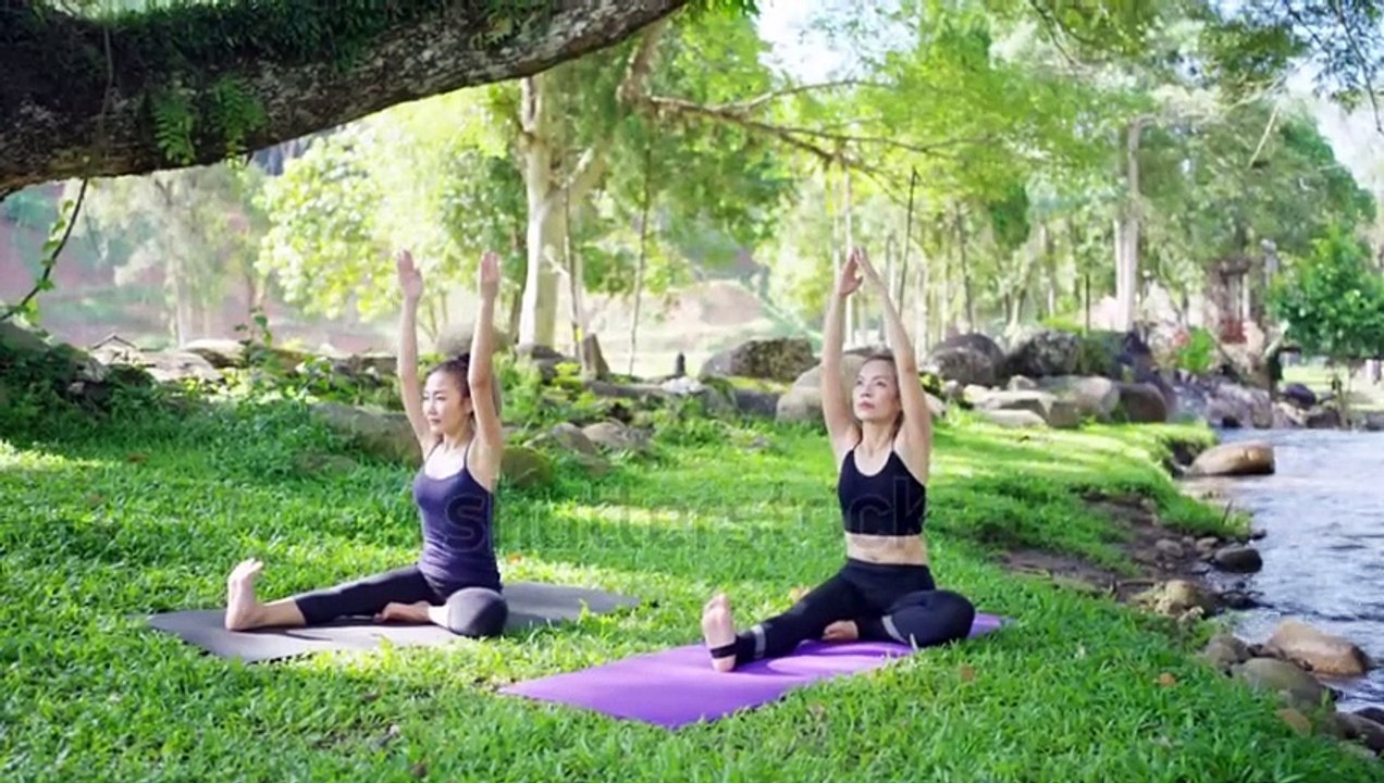 stock-footage-asian-woman-practicing-yoga-exercise-on-yoga-mat-with-yoga-teacher-in-yoga-class-at-natural-park