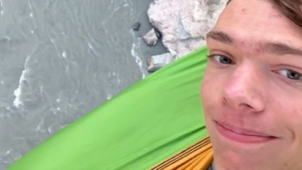 Fearless lad chills in a hammock... suspended from a BRIDGE!