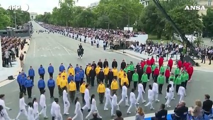 Parigi 2024, la fiaccola olimpica sfila con i militari per il 14 luglio