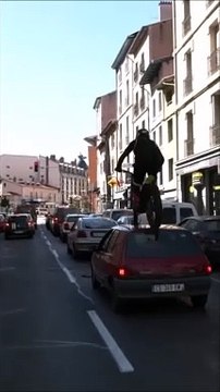 Un motard escalade des voitures garée avec sa motocross (France)