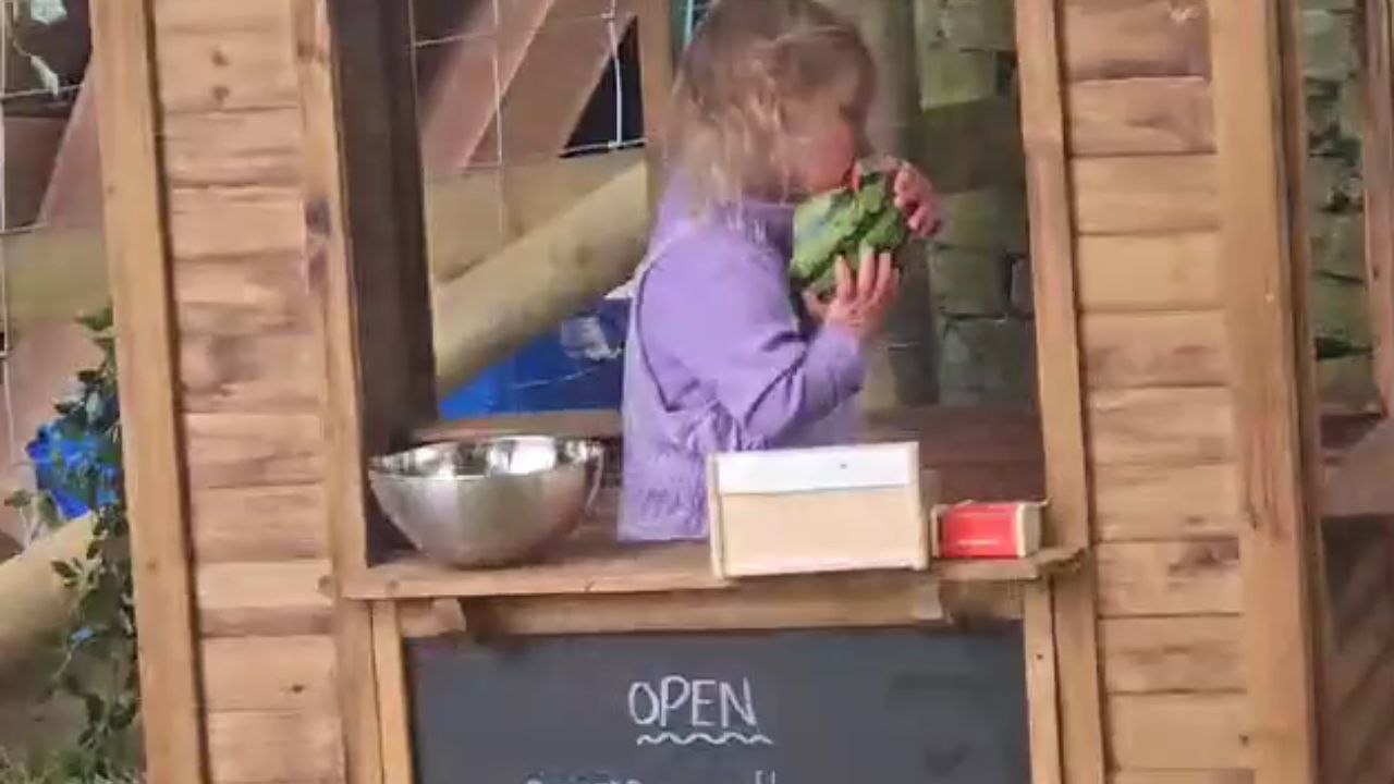 Mom captures daughter's funny watermelon escapade during playful adventure in outdoor fruit market