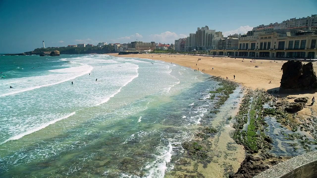Ocean waves bursting on the shore of the coast Ocean waves bursting on the shore of sand and rocks on a clear day