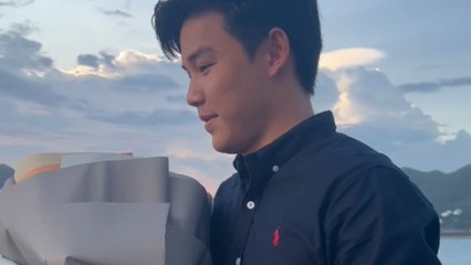 Boy proposes girlfriend at the seaside with a ring and bouquet