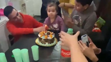 Little girl blows out candle on her first birthday with a finger