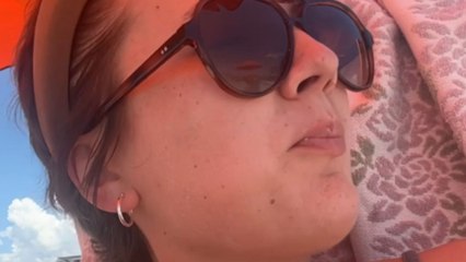 Woman's relaxing beach picnic interrupted by surprise bug landing on shoulder