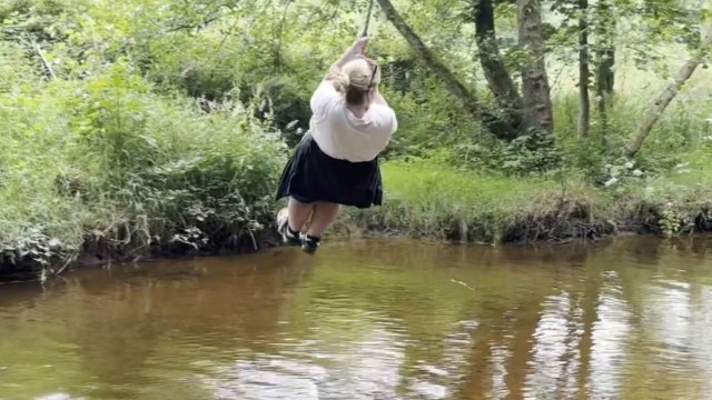 Woman fails to cap off rope swing fun with proper landing, resulting in a splash in muddy water