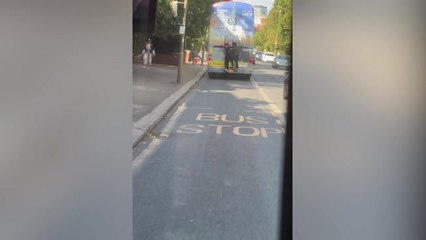 Two people in London seen surfing a bus