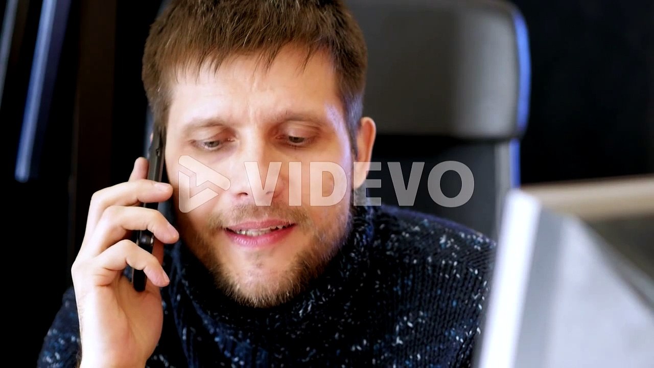 Man using computer and talking on cell phone