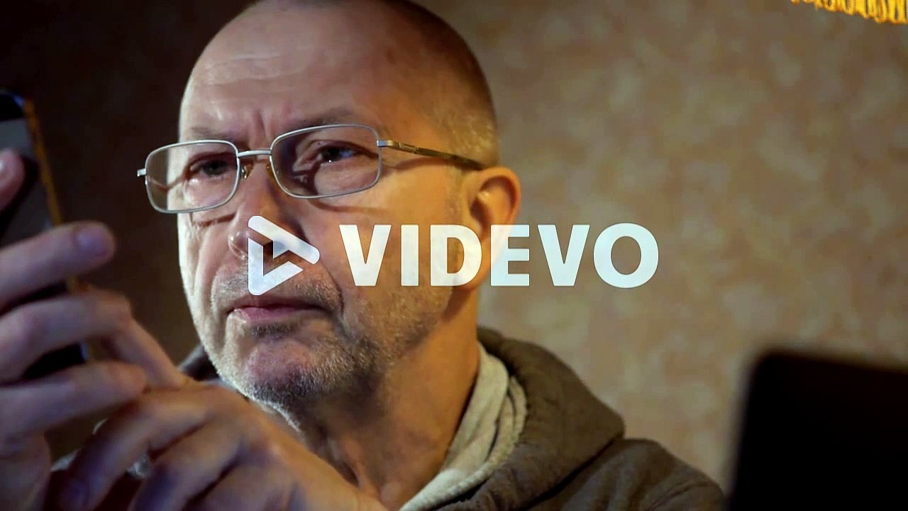 older man using a laptop and talking on the phone