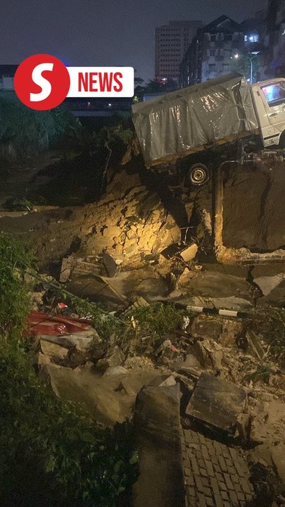 Prolonged heavy rain causes riverbank to collapse, damaging two vehicles