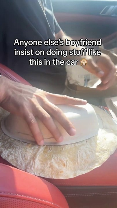 Guy is making a Chipotle burrito on the arm rest in the car!