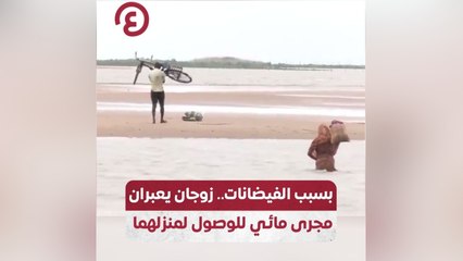 بسبب الفيضانات.. زوجان يعبران مجرى مائي للوصول لمنزلهما