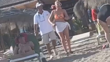 Unaware beachgoer causes drink disaster while dancing her way toward friends