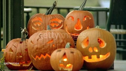 MEDIUM ANGLE OF TWO ROWS OF JACK-O-LANTERNS CARVED IN VARIOUS EXPRESSIONS ON PORCH WITH CANDLE LIGHT FLICKERING INSIDE. HALLOWEEN. - HD stock videogettyimages-1007997314-640_adpp