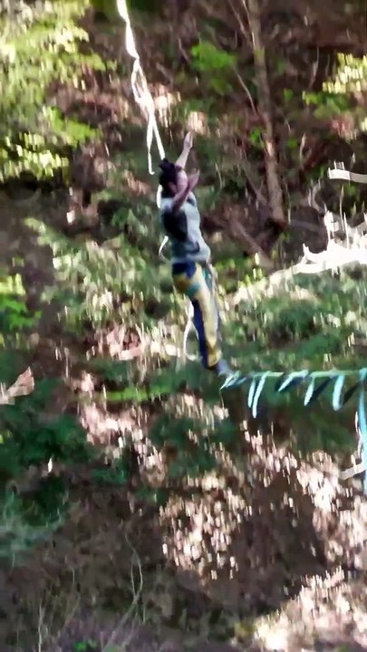 Person is doing flips while highlining in the woods!