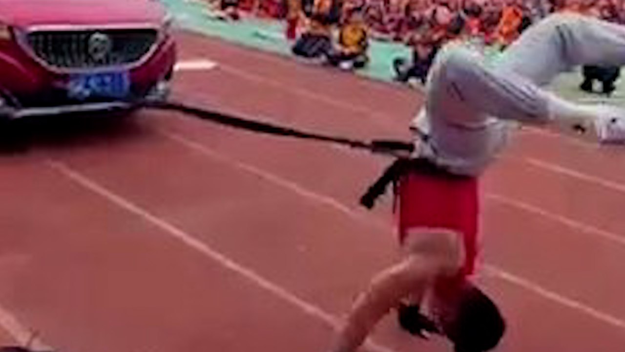 Chinese teacher pulls car while doing handstand