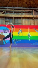 Woman is doing a handstand while hula hooping with her foot!