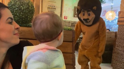 The cute baby becomes upset when interacting with someone dressed as a lion.