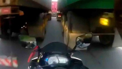 動画：オートバイ運転手が2台のトラックの間を通ろうとして挟まれる瞬間
