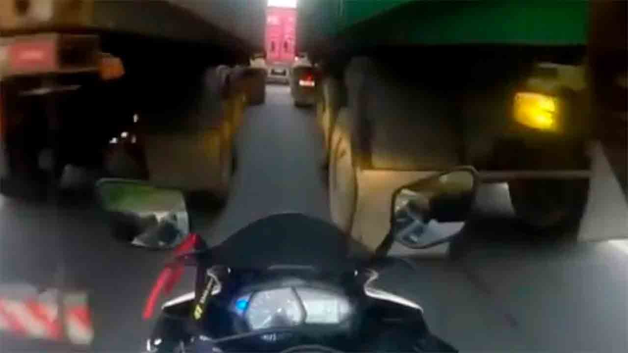 動画：オートバイ運転手が2台のトラックの間を通ろうとして挟まれる瞬間