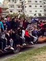 Locals ride on a collapsed monument to the former president of Syria